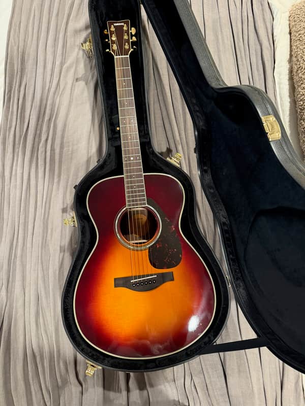 A light yellow acoustic guitar with a dark brown pickguard and wood grain.
