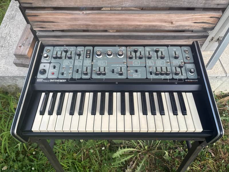 Black synthesizer keyboard with white keys, showing knobs and controls.