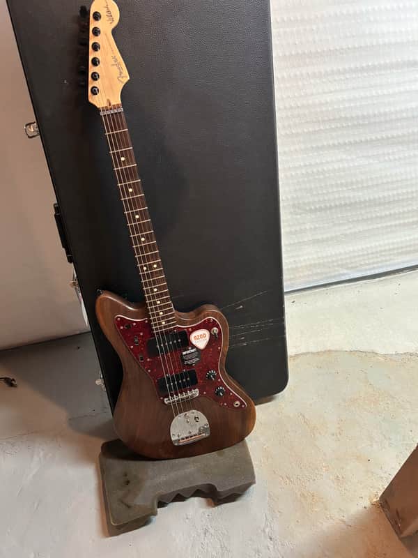 Orange electric guitar in open black velvet-lined presentation case.