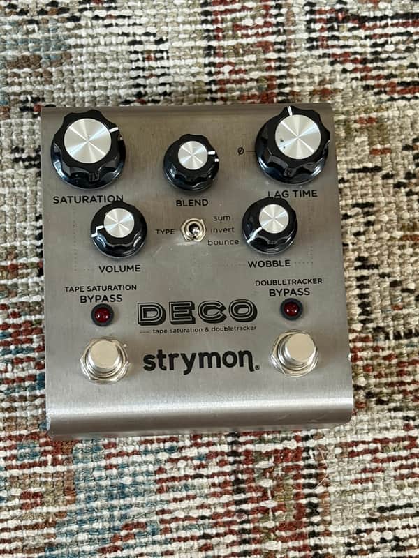 Silver Strymon DECO pedal with knobs, visible on black surface.