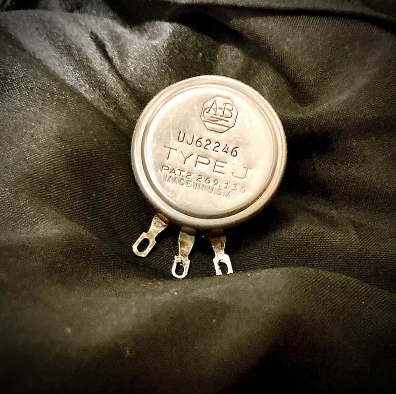 Silver and brass mechanical components, one with "AB" and "UJ-62689" markings.