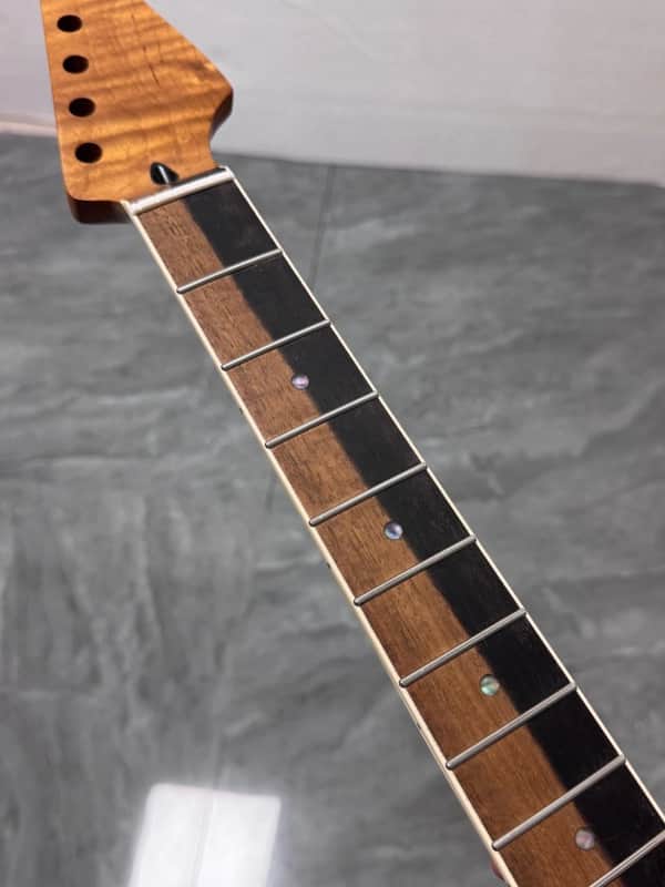 Close-up of a dark wood guitar fretboard with visible frets and inlays.