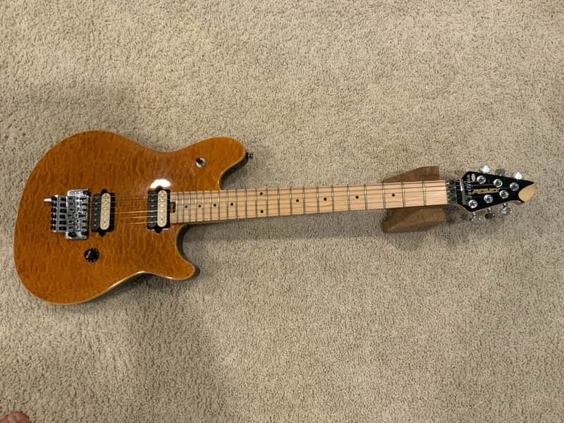 Green electric guitar with gold hardware, resting on blue and gray fabric.