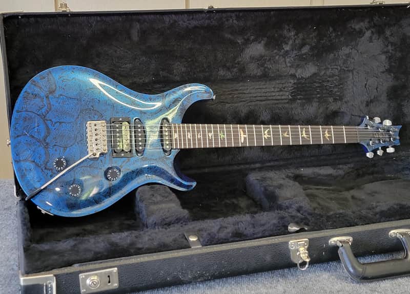 Yellow electric guitar in open black velvet case with accessories.