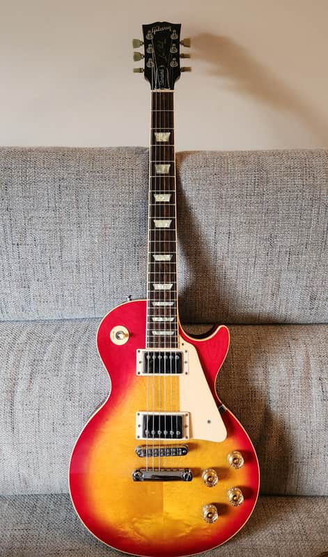 Brown electric guitar, partially visible, resting on a wooden stand.
