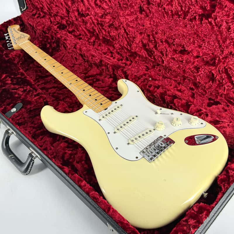 Yellow electric guitar in red velvet case, showing fretboard and pickups.