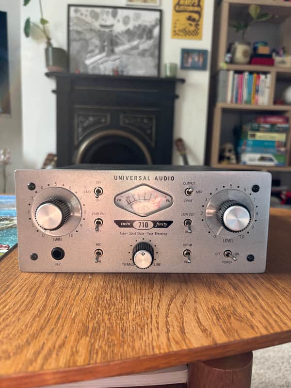 Silver audio mixer with knobs and meters on a wooden surface.