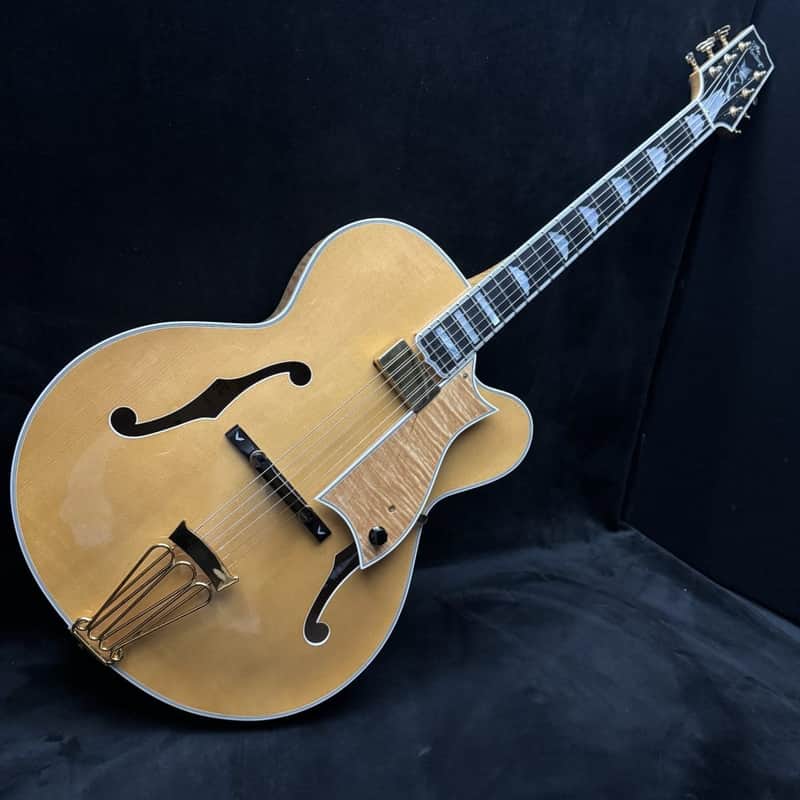 Light brown acoustic guitar displayed on brown leather couch.