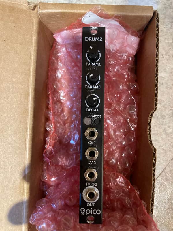 Black electronic module with knobs and jacks, next to white and pink ribbon cable.
