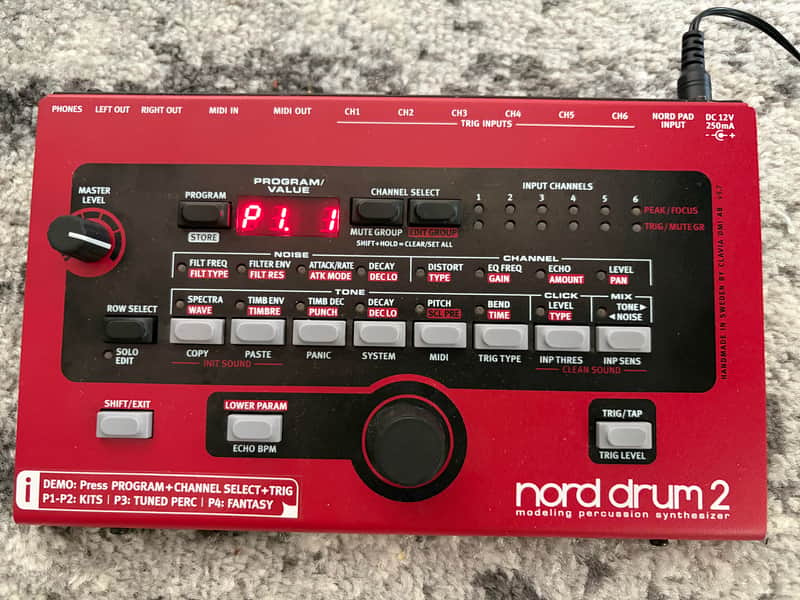 Red Nord Drum 2 synthesizer and black drum pad shown together.