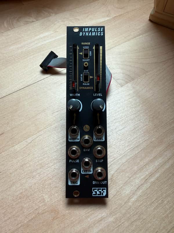Black Impulse Dynamics effects pedal with various knobs and switches visible.