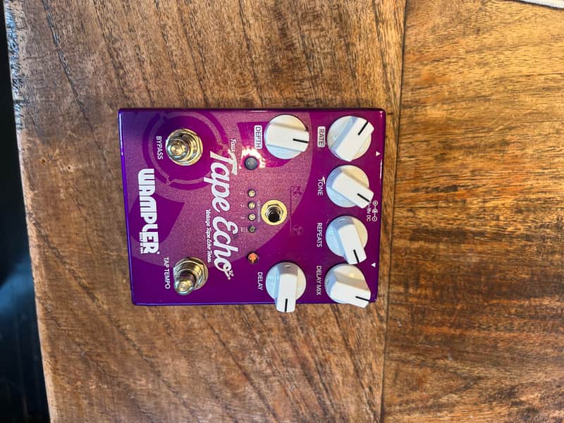 Purple stompbox pedal with white knobs and silver jacks. Wampler Tape Echo.
