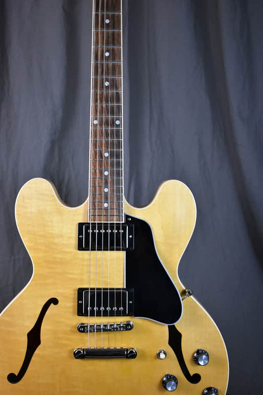 Yellow electric guitar in black case, visible hardware, on patterned cloth.