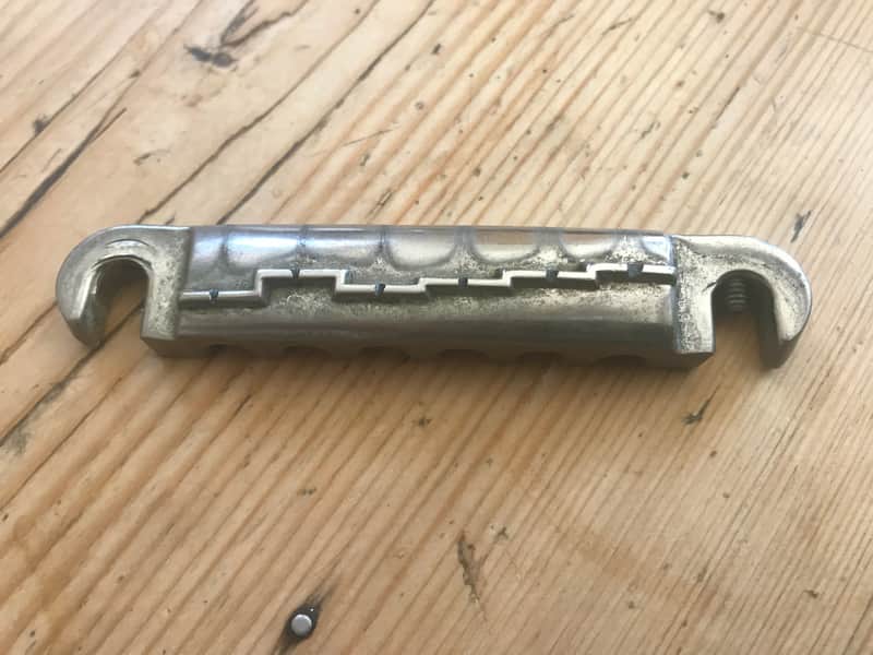 Chrome metal hook and two silver screws on a wooden surface.