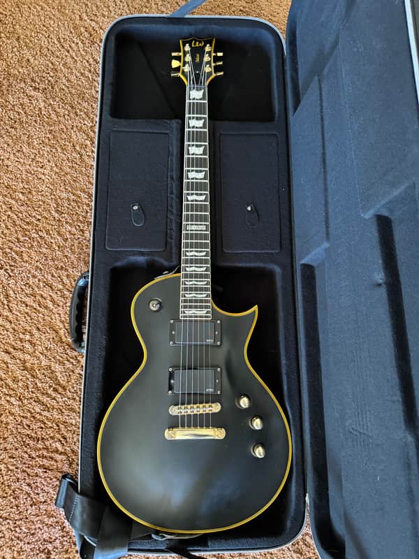 Dark blue electric guitar resting on a patterned rug.