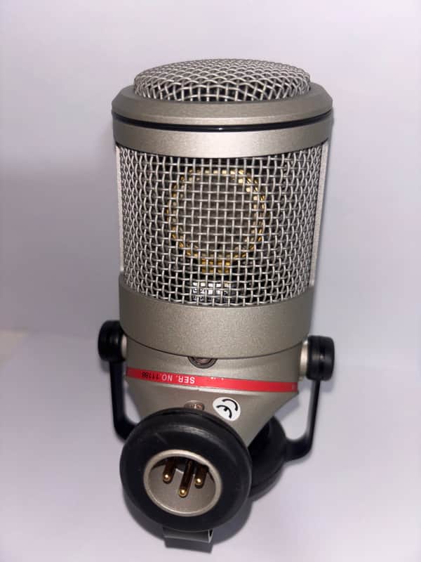 Black tumbler with "NEUMANN.BERLIN" logo next to vintage microphone.