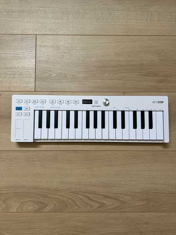 White electronic keyboard with black and white keys, resting on a white surface.
