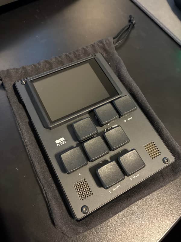 Black handheld electronic device with screen and keypad in carrying case.