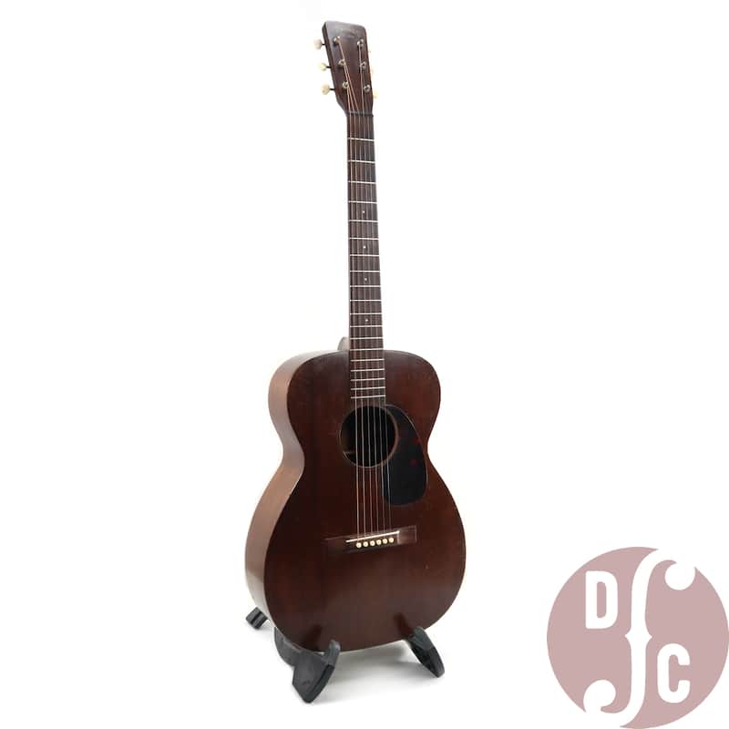 Acoustic guitar in natural wood, resting on a patterned, brown carrying case.