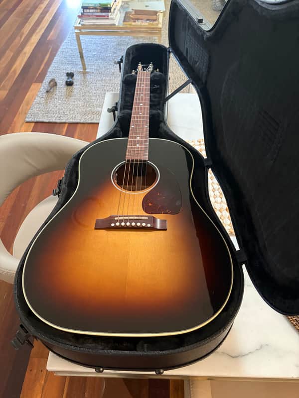 Gibson acoustic guitar with sunburst finish next to black guitar body.