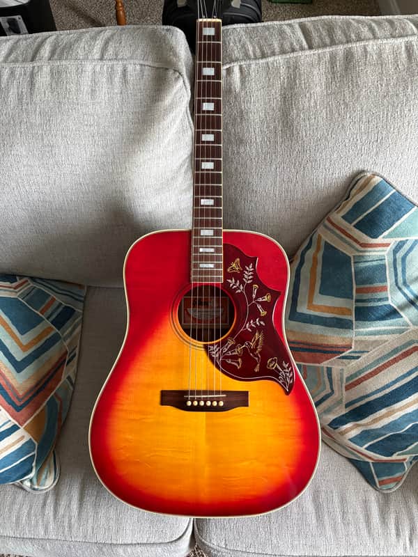 Acoustic guitar in a burgundy velvet-lined case; brown wood finish.