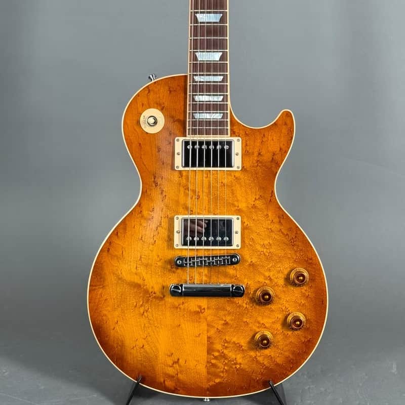 Brown electric guitar, partially visible, resting on a wooden stand.