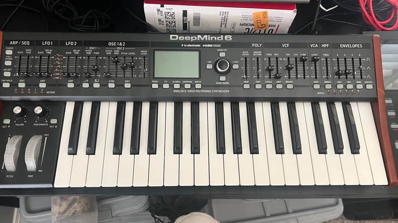 Black and wood DeepMind 6 synthesizer with white keys and knobs.