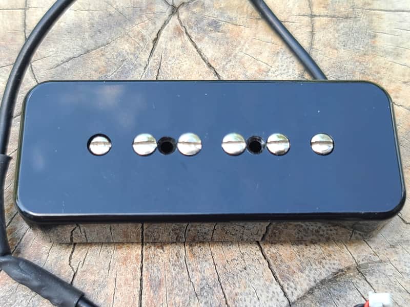 Two cream-colored guitar strap buttons on a wooden surface.