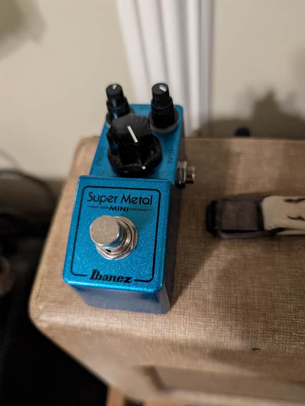 Blue guitar effects pedal with knobs, jacks, and "Super Metal" branding.