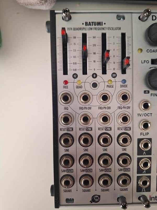 White electronic oscillator with black knobs and red indicator lights.