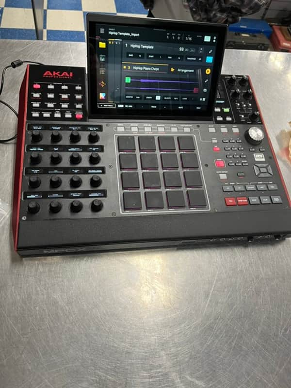 Grey and red mixing console with digital screen, resting on gray carpet.