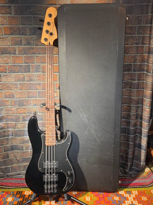 Cream and black electric guitar resting on a black and white patterned sheet.