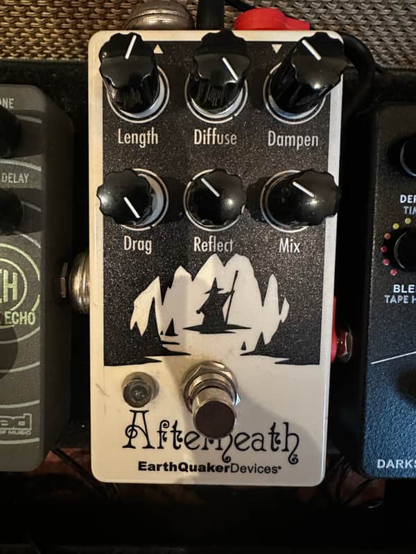 Black knobs on a cream-colored effects pedal with a mountain graphic.