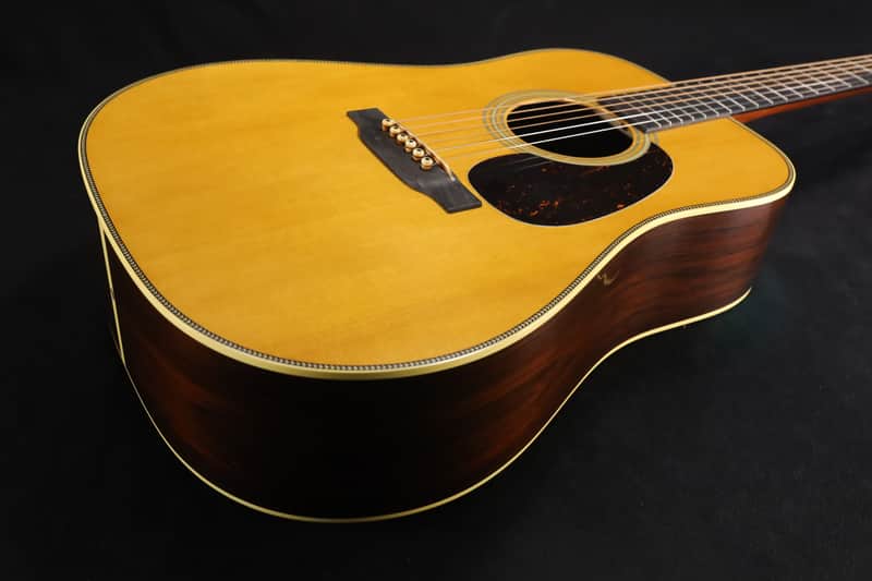 A vintage acoustic guitar with colorful graphic on the body, next to its case.