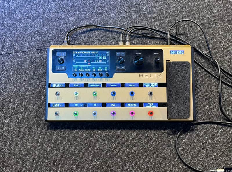Grey electronic music mixer/effects unit on a stand, visible controls and display.