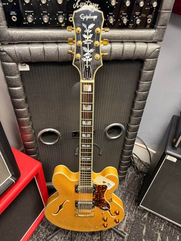 Black electric guitar with chrome hardware, displayed on a textured surface.