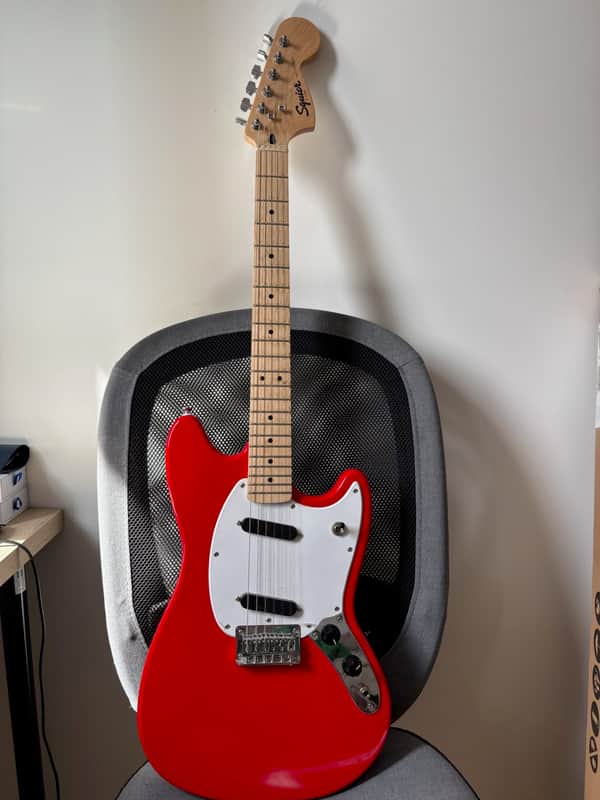 Bright blue electric guitar with silver hardware, resting on dark textured surface.