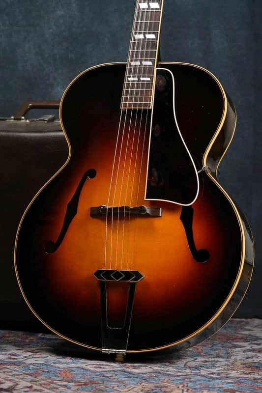 Brown acoustic guitar, visible soundhole and bridge, against a white wooden background.