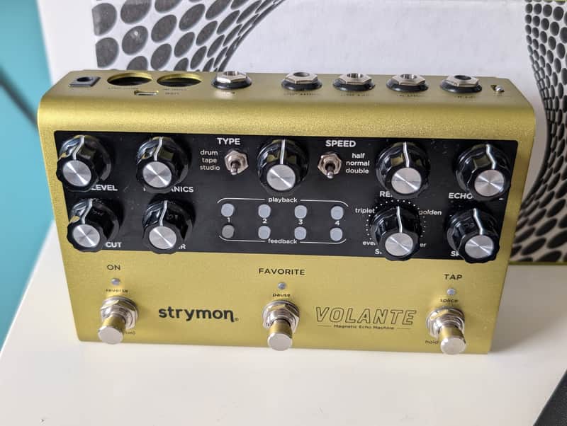 Black stompbox guitar effects pedal with knobs and switches on wood surface.