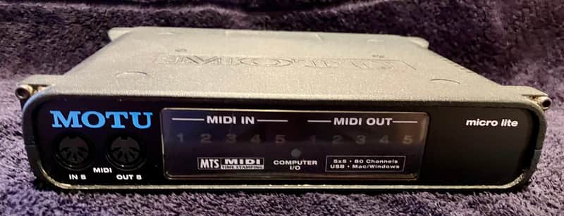 Gray MOTU audio interface with visible MIDI in and out ports.