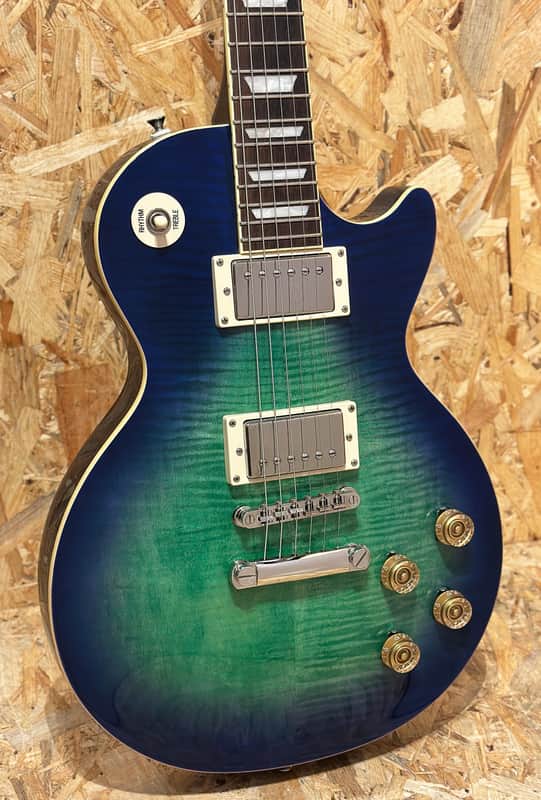 Brown electric guitar with gold hardware, resting on gray fabric.