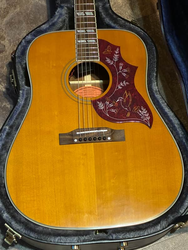 Yellow acoustic guitar with red floral inlay on the body.
