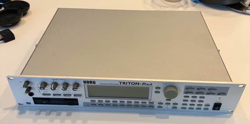 White and black Korg Triton Rack synthesizer on a red tiled surface.
