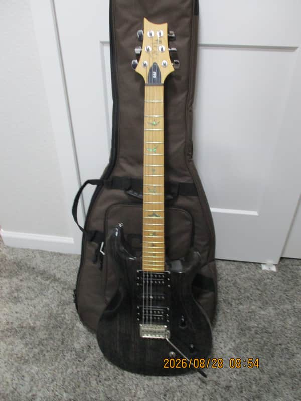 Orange and brown electric guitar body with black strap, resting on black case.