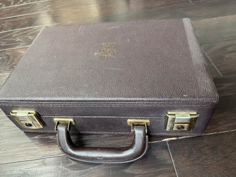 Two black and gold musical instruments in open purple velvet case.