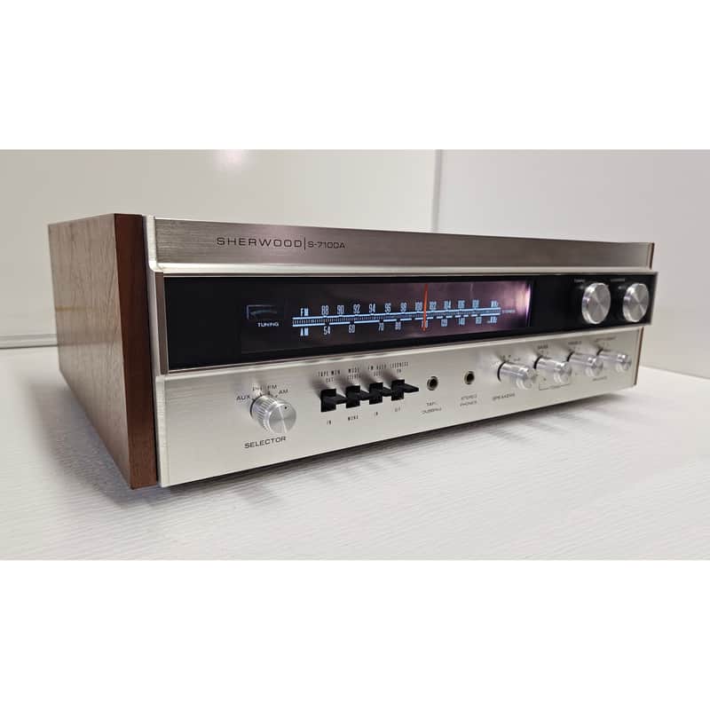 Silver and wood stereo receiver with tuning display and knobs.