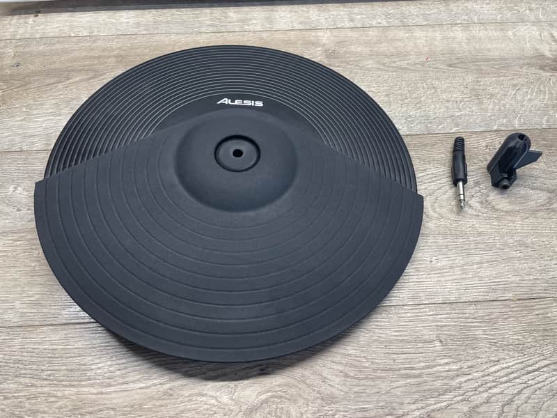 Gray Alesis turntable on light wood surface with small black accessory.