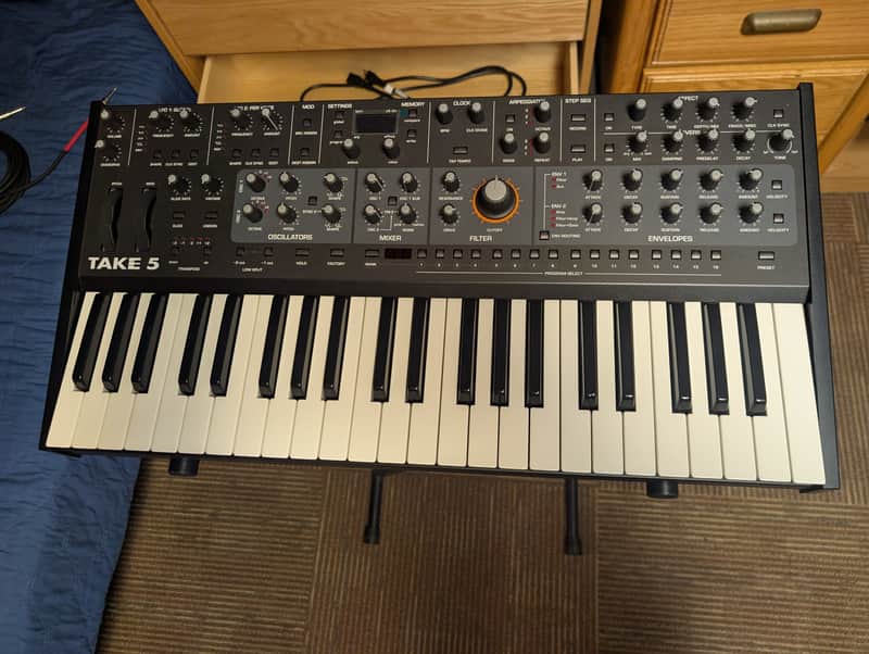 Black and white electronic keyboard on a shelf, visible keys and controls.