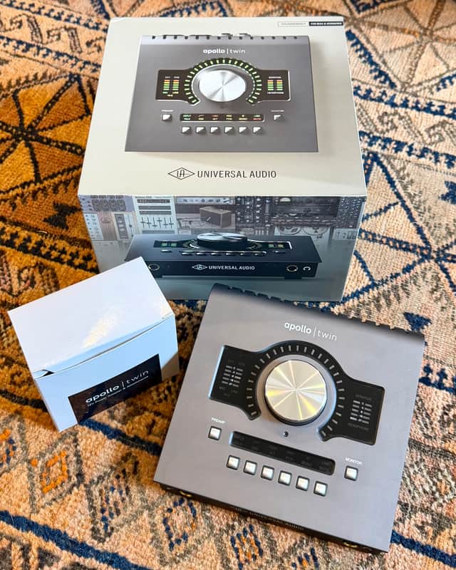 Silver audio mixer with "apollo twin" branding and various knobs and controls.