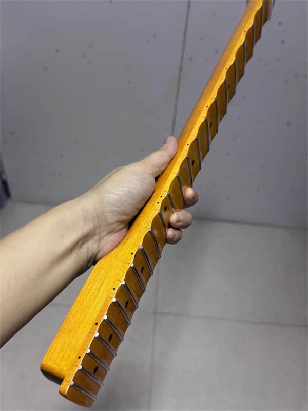 Close-up of a dark wood guitar fretboard with visible frets and inlays.